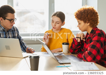 Teamwork brainstorm. Diverse colleagues working together discuss financial statistics. Group of happy young modern people sitting in creative office discussing business. Young professional team 136055325