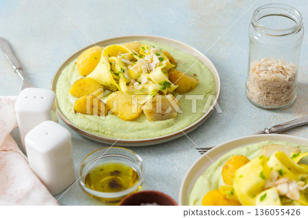 Baked potatoes are topped with slices of fermented zucchini and served alongside a green pea sauce with broccoli. This meal is prepared for a healthy breakfast Baked potatoes are topped with slices of fermented zucchini and served alongside a green pea sauce with broccoli. This meal is prepared for a healthy breakfast 136055426