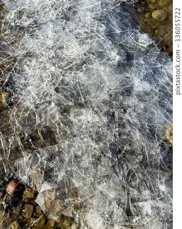 fragile cracked ice on the rocky shore of the lake fragile cracked ice on the rocky shore of the lake 136055722