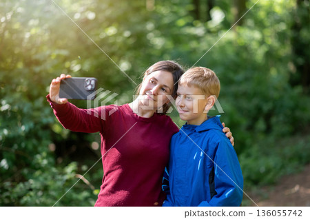 Happy mother and son taking a selfie together in a spring park, enjoying cheerful family moments outdoors 136055742
