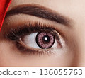striking close up of a woman eyes accentuated by pink contact lenses, bold lashes, and shimmering makeup. Red framing the gaze, conveying fashion, confidence, and contemporary beauty 136055763