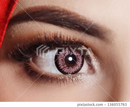 striking close up of a woman eyes accentuated by pink contact lenses, bold lashes, and shimmering makeup. Red framing the gaze, conveying fashion, confidence, and contemporary beauty 136055763