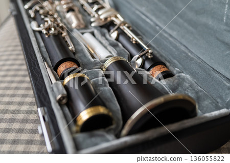 A black clarinet rests in an open case with a plush interior. The selective focus highlights its silver keys and sleek body, while the blurred background adds depth. A perfect shot for music and 136055822