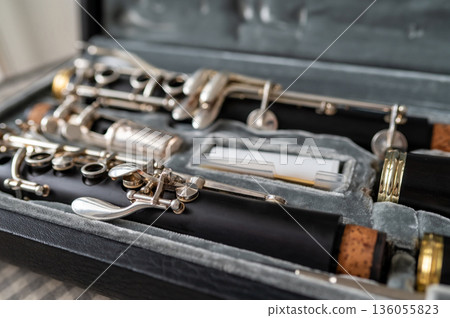 A black clarinet rests in an open case with a plush interior. The selective focus highlights its silver keys and sleek body, while the blurred background adds depth. A perfect shot for music and instr A black clarinet rests in an open case with a plush interior. The selective focus highlights its silver keys and sleek body, while the blurred background adds depth. A perfect shot for music and instr 136055823