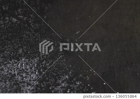 wet black uneven and embossed black slate for serving, covered with lots of water drops kitchen board made of black embossed slate, close up 136055864