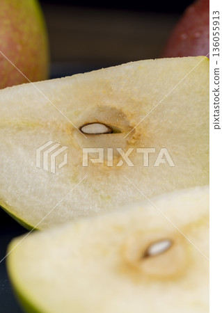 sliced green-red pears on a blue ceramic bowl on the table, several ripe hard and juicy pears are lying on a bowl on the kitchen table, the pears are covered with drops of water sliced green-red pears on a blue ceramic bowl on the table, several ripe hard and juicy pears are lying on a bowl on the kitchen table, the pears are covered with drops of water 136055913