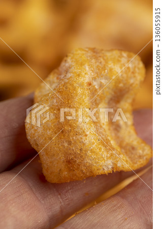 crispy mashed potato chips fried in a large amount of sunflower oil, sprinkled with red hot pepper , crispy delicious high-calorie chips with spices are scattered on the table crispy mashed potato chips fried in a large amount of sunflower oil, sprinkled with red hot pepper , crispy delicious high-calorie chips with spices are scattered on the table 136055915