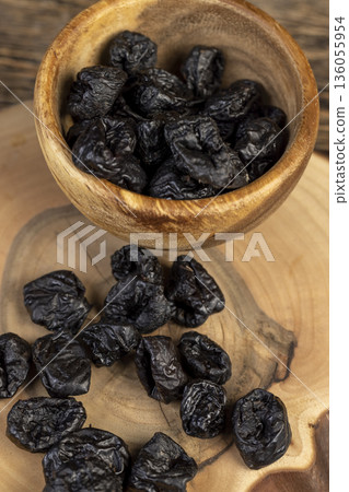 black soft dehydrated fruits of black plums, prunes on the kitchen table, black sweet seedless prunes scattered on the table 136055954