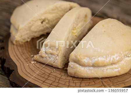 sliced fresh shortbread bun with juicy curd filling on a wooden board on the table, close up 136055957