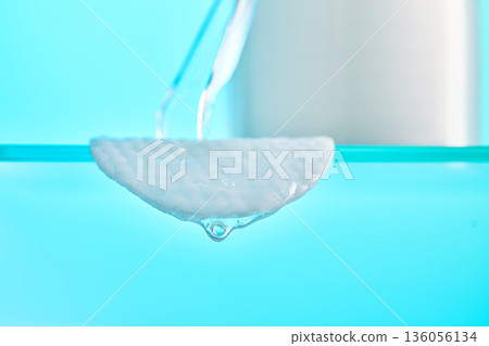 Micellar liquid dropping from a cotton pad 136056134