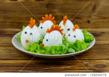 Funny easter breakfast with boiled eggs as chicks on wooden table Funny easter breakfast with boiled eggs as chicks on wooden table 136056578