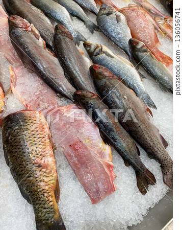 Fresh gutted fish displayed on crushed ice at a seafood market, ready for sale or cooking preparation Fresh gutted fish displayed on crushed ice at a seafood market, ready for sale or cooking preparation 136056741
