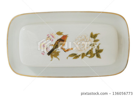 Porcelain dish for butter with a pattern of birdie isolated on a white background. Butter crock. Ornate ceramic dinnerware. Top view. Porcelain dish for butter with a pattern of birdie isolated on a white background. Butter crock. Ornate ceramic dinnerware. Top view. 136056773
