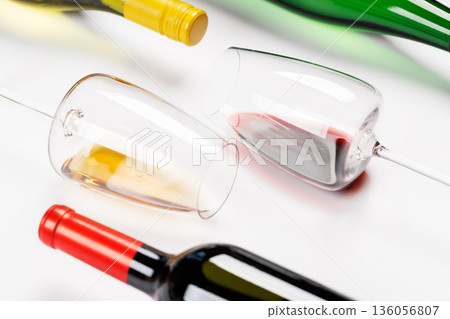 Wine glasses with red and white wine and bottles lying on white background Wine glasses with red and white wine and bottles lying on white background 136056807