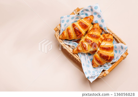 Freshly baked croissants in wicker basket on light background 136056828