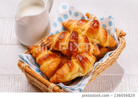 Aromatic croissants in wicker basket with milk jug Aromatic croissants in wicker basket with milk jug 136056829