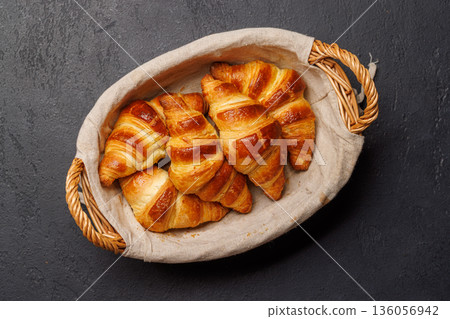 Freshly baked croissants in wicker basket on dark background Freshly baked croissants in wicker basket on dark background 136056942