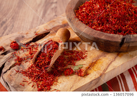 Spice saffron threads, in a wooden bowl, on a wooden table, top view, close-up, 136057096