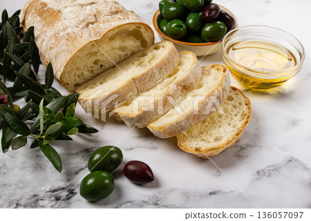 appetizer, sliced ciabatta bread, with olive oil, green olives, Chalkidiki olives, classic Green green olive, on a marble table, top view, no people, 136057097