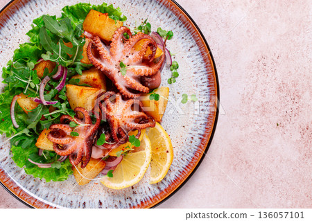 Grilled octopus with baked potatoes and fresh herbs, on a decorative plate, homemade, 136057101