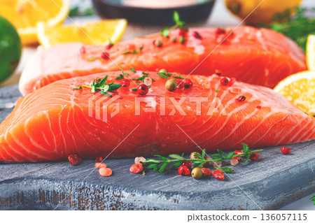 Fresh salmon fillets with herbs and citrus on a wooden cutting board at a kitchen counter ready for cooking 136057115