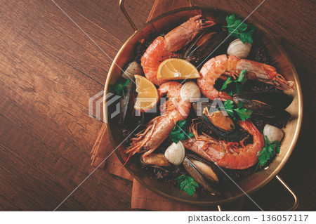 seafood and black rice paella, in a frying pan, homemade, on a wooden table, no people, seafood and black rice paella, in a frying pan, homemade, on a wooden table, no people, 136057117
