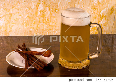 Glass with amazing beer and a plate with a snack on the table Glass with amazing beer and a plate with a snack on the table 136057296