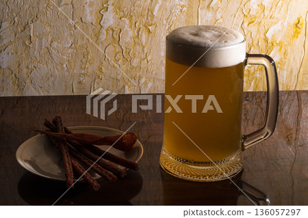 Glass with amazing beer and a plate with a snack on the table Glass with amazing beer and a plate with a snack on the table 136057297