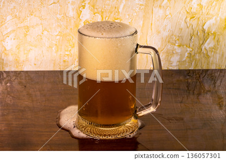 Glass with amazing beer that partially spilled on the table 136057301
