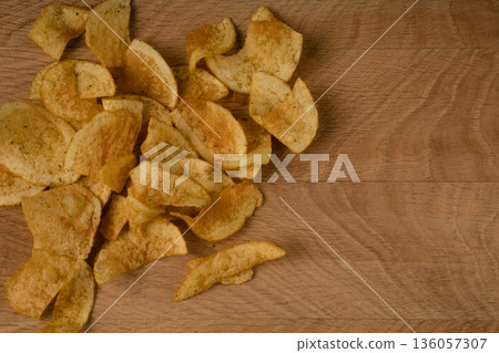 Appetizing potato chips are scattered on a wooden board 136057307