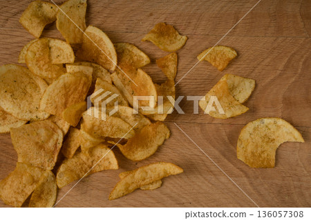 Appetizing potato chips are scattered on a wooden board Appetizing potato chips are scattered on a wooden board 136057308