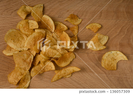 Appetizing potato chips are scattered on a wooden board 136057309