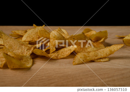 Appetizing potato chips are scattered on a wooden board 136057310