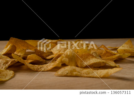 Appetizing crispy potato chips scattered on a wooden board Appetizing crispy potato chips scattered on a wooden board 136057311
