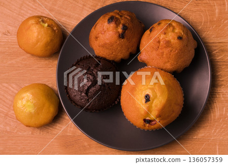 Cupcakes and popcorn in a black plate and on a wooden board Cupcakes and popcorn in a black plate and on a wooden board 136057359