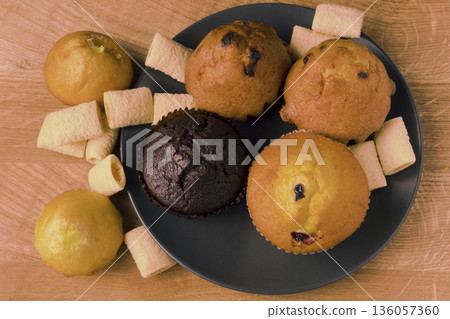 Cupcakes and popcorn in a black plate and on a wooden board 136057360