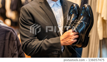 Shoe store. Business man choose elegant footwear in shop. Classic leather shoes for formal look. Formal shoe. Leather footwear. Shop assistant man in shoe store hold classic footwear, cropped view 136057475