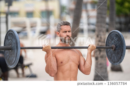 Sport motivation. Muscular man do sport exercise. Gym workout. Sport athlete man with barbell. Barbell training. Mature man exercising with barbell outdoor. Man athlete lifting barbell Sport motivation. Muscular man do sport exercise. Gym workout. Sport athlete man with barbell. Barbell training. Mature man exercising with barbell outdoor. Man athlete lifting barbell 136057784