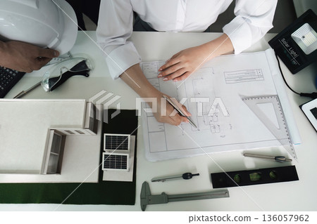 A man and a woman are working on a drawing of a building A man and a woman are working on a drawing of a building 136057962