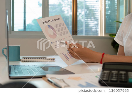Financial Planning. Individual analyzing budget pie chart at home office. Financial Planning. Individual analyzing budget pie chart at home office. 136057965