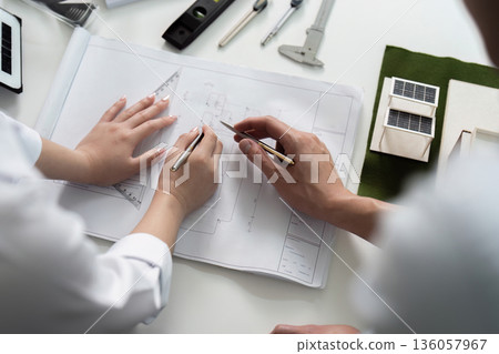 Two people are drawing on a white sheet of paper Two people are drawing on a white sheet of paper 136057967