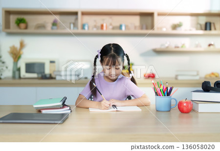 Back to School. Young girl studying and writing in notebook at home. 136058020