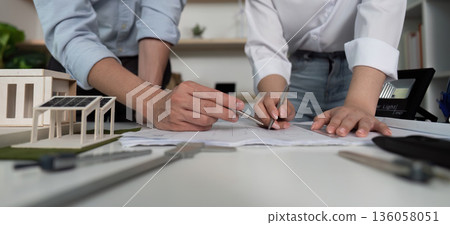 Two people are working on a drawing of a house Two people are working on a drawing of a house 136058051