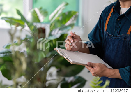 A man is holding a clipboard and writing on it 136058067