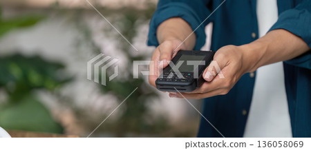 A person is holding a black device in their hand 136058069