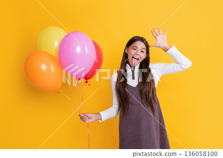 cheerful child with party helium balloons on yellow background cheerful child with party helium balloons on yellow background 136058100