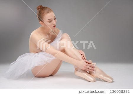 Captivating ballet dancer gracefully preparing for performance Captivating ballet dancer gracefully preparing for performance 136058221