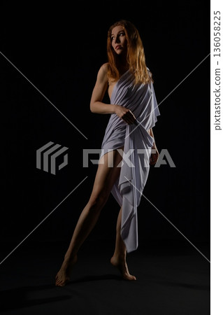 Woman gracefully dancing under soft lighting in a dark setting Woman gracefully dancing under soft lighting in a dark setting 136058225