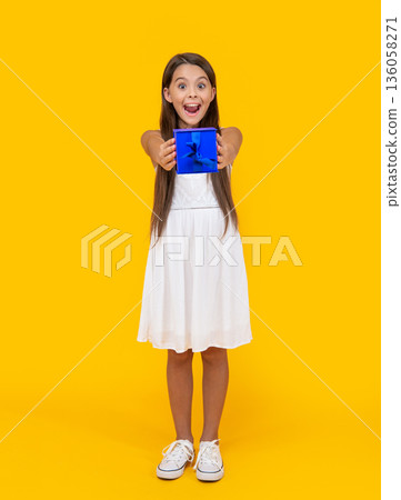amazed teen child hold present box on yellow background 136058271