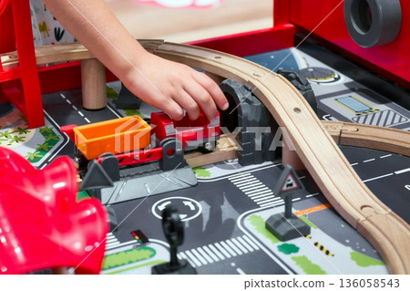 Close-up of a child's arm and hand playing with a toy train set Close-up of a child's arm and hand playing with a toy train set 136058543